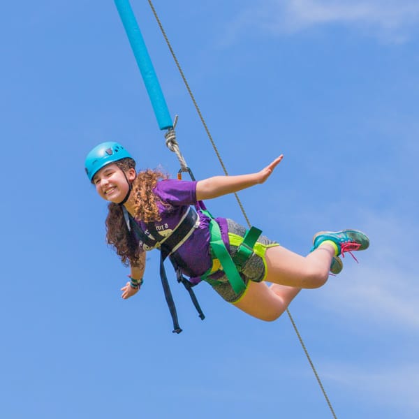 Girl on high ropes course pretending to fly